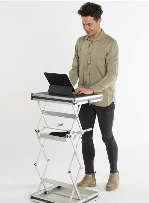 Man staat recht achter een opvouwbare, verstelbare werktafel en werkt op een tablet op witte achtergrond.